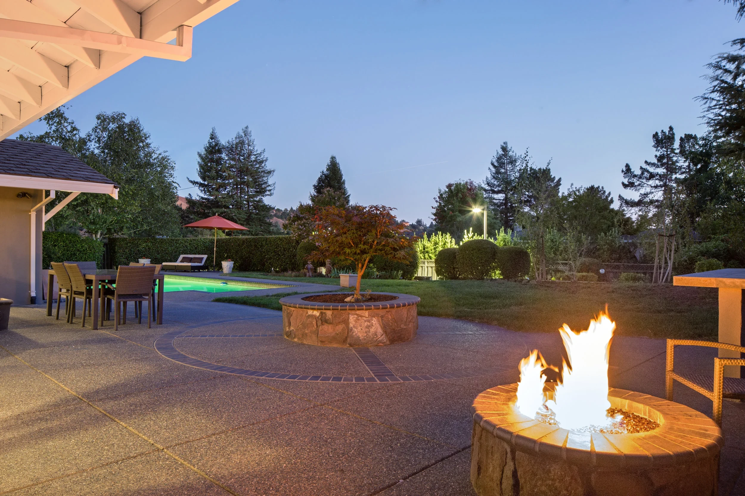 Backyard patio fire pit and pool at dusk